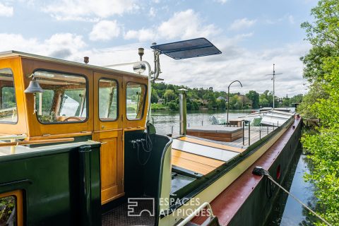 Large and bright barge on the banks of the Seine with terrace