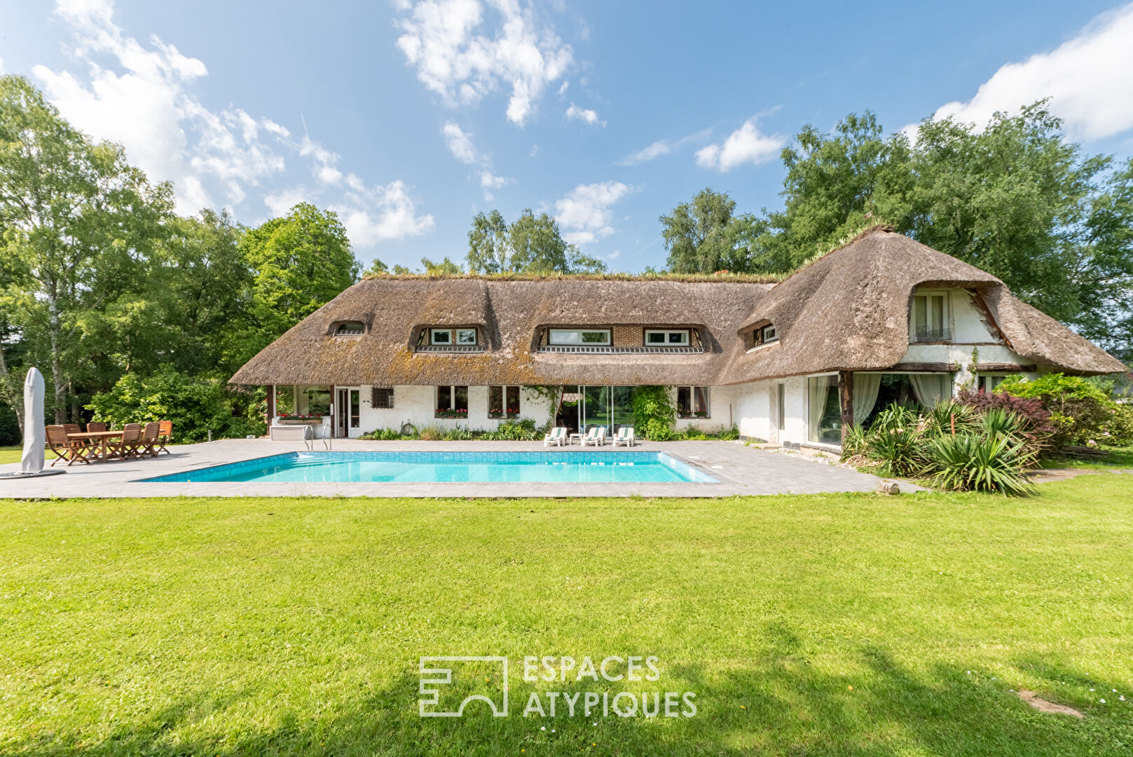 Thatched cottage with swimming pool in a green setting