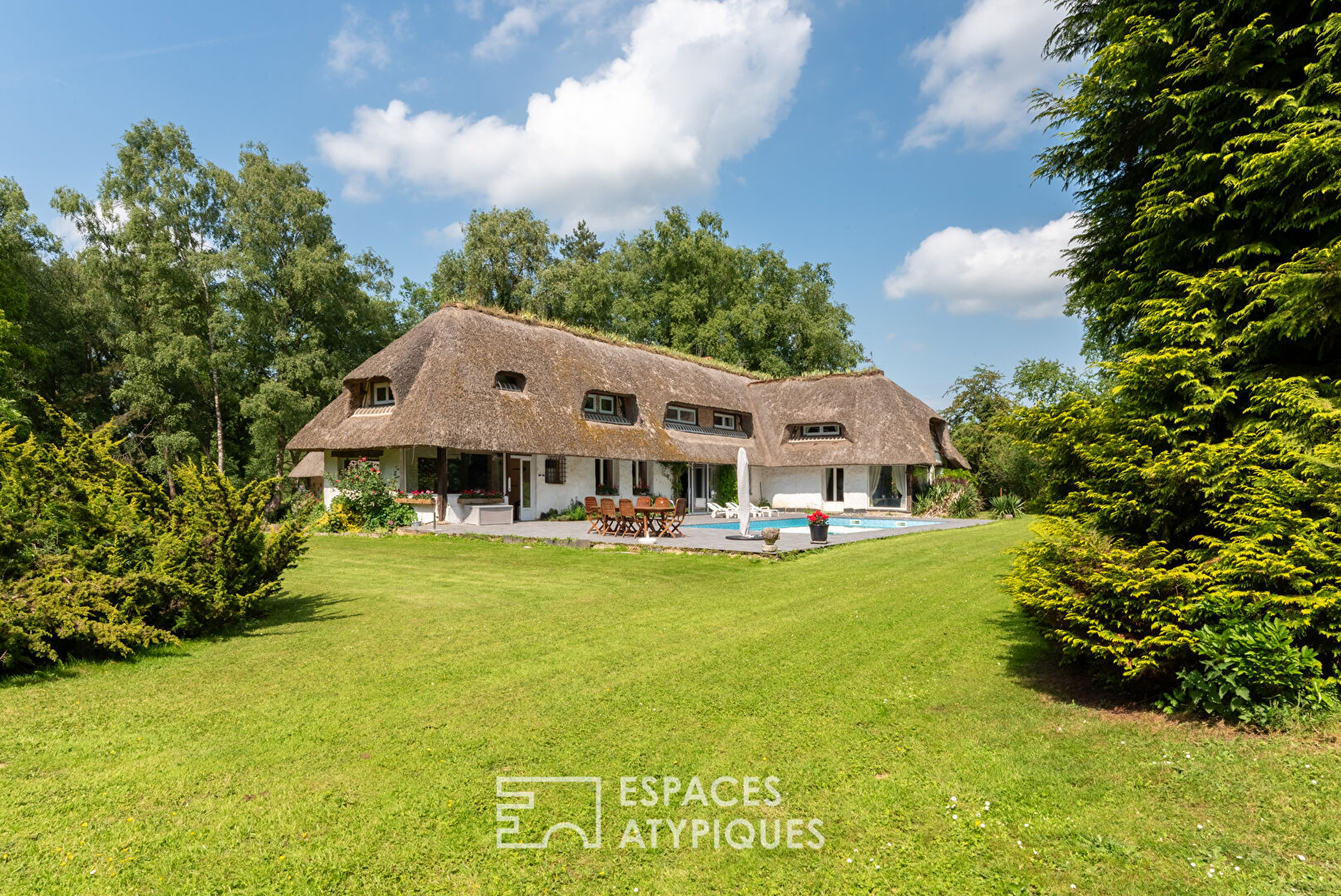 Thatched cottage with swimming pool in a green setting
