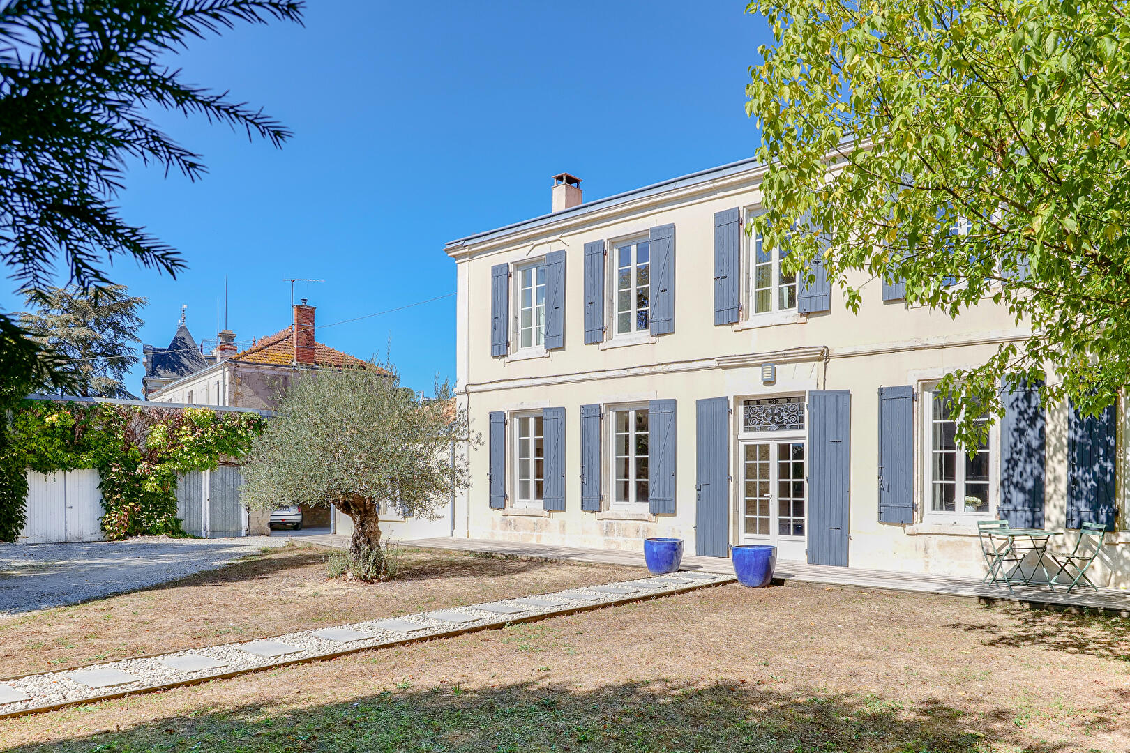 Maison de maître en pierre blanche aux volets bleu-gris et toit d'ardoise, avec son jardin, près de La Rochelle