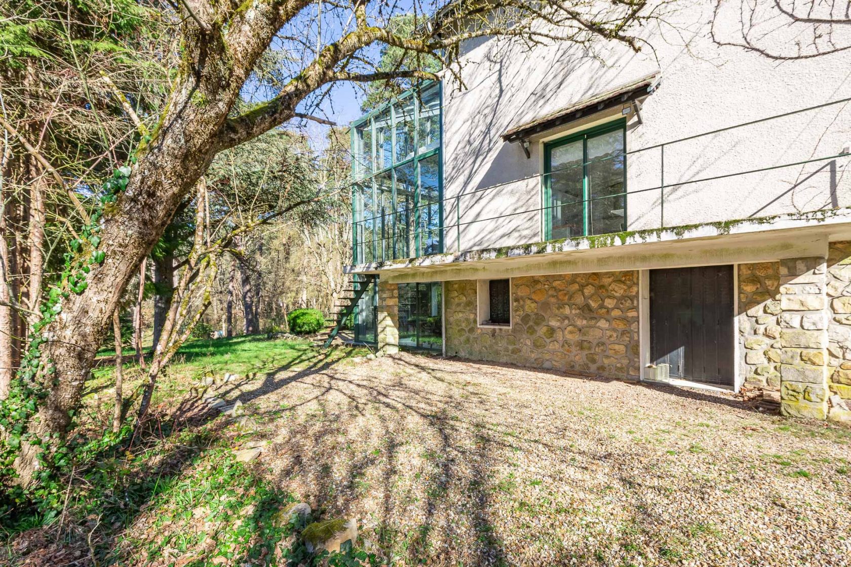 Maison avec son extension verrière nichée dans la forêt