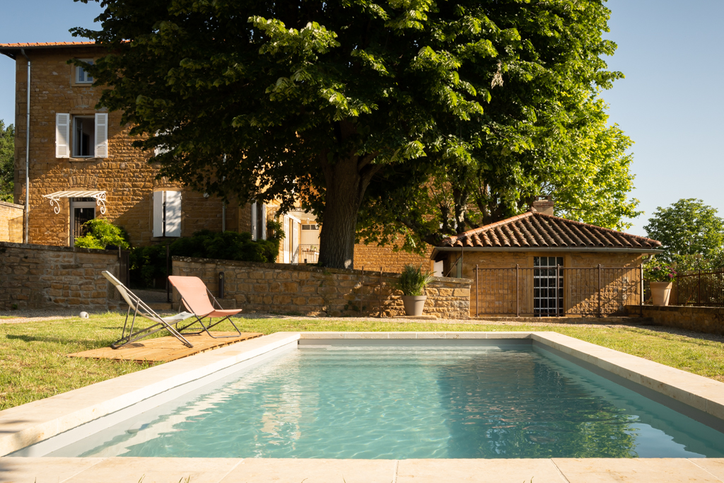 Golden stone building with swimming pool and outbuilding