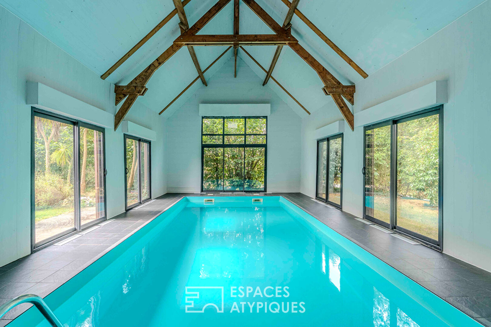 Villa contemporaine avec piscine intérieure dans un écrin de verdure.
