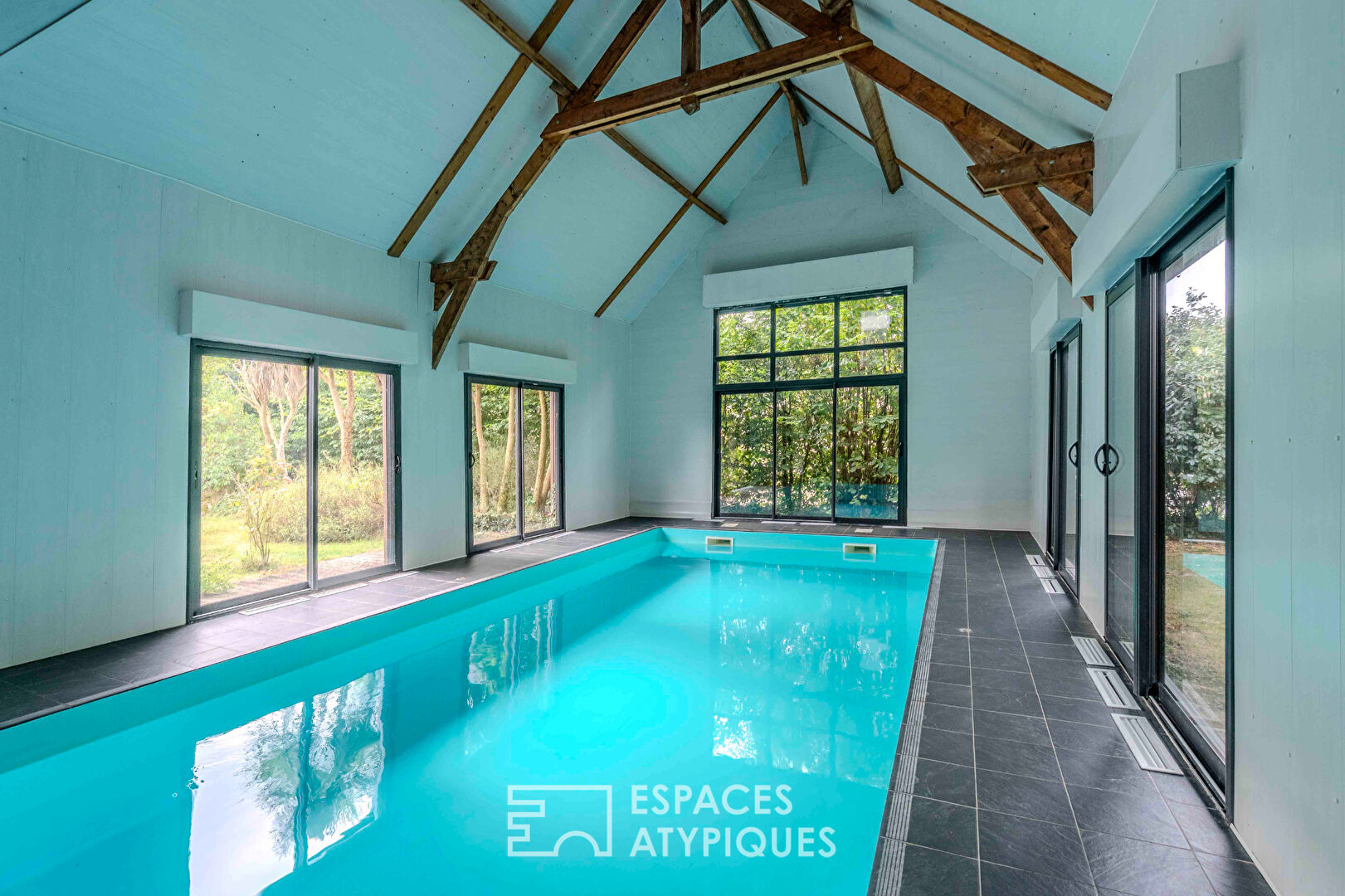 Villa contemporaine avec piscine intérieure dans un écrin de verdure.