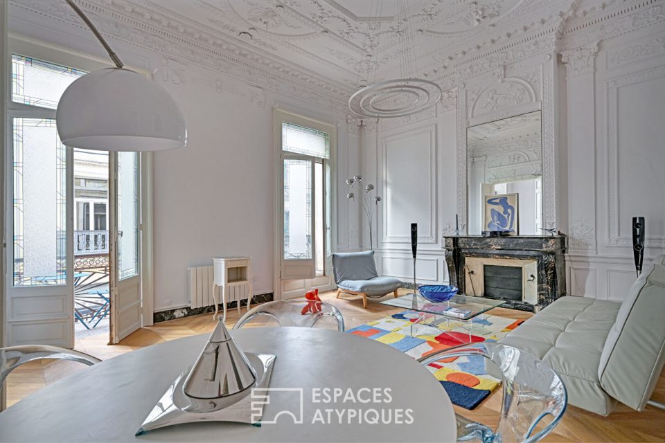 Salon d'un appartement Haussmannien, avec cheminée en marbre, lustre, parquet et moulures
