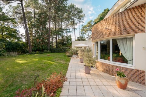 Maison d’Architecte avec jardin paysager dans un environnement boisé.