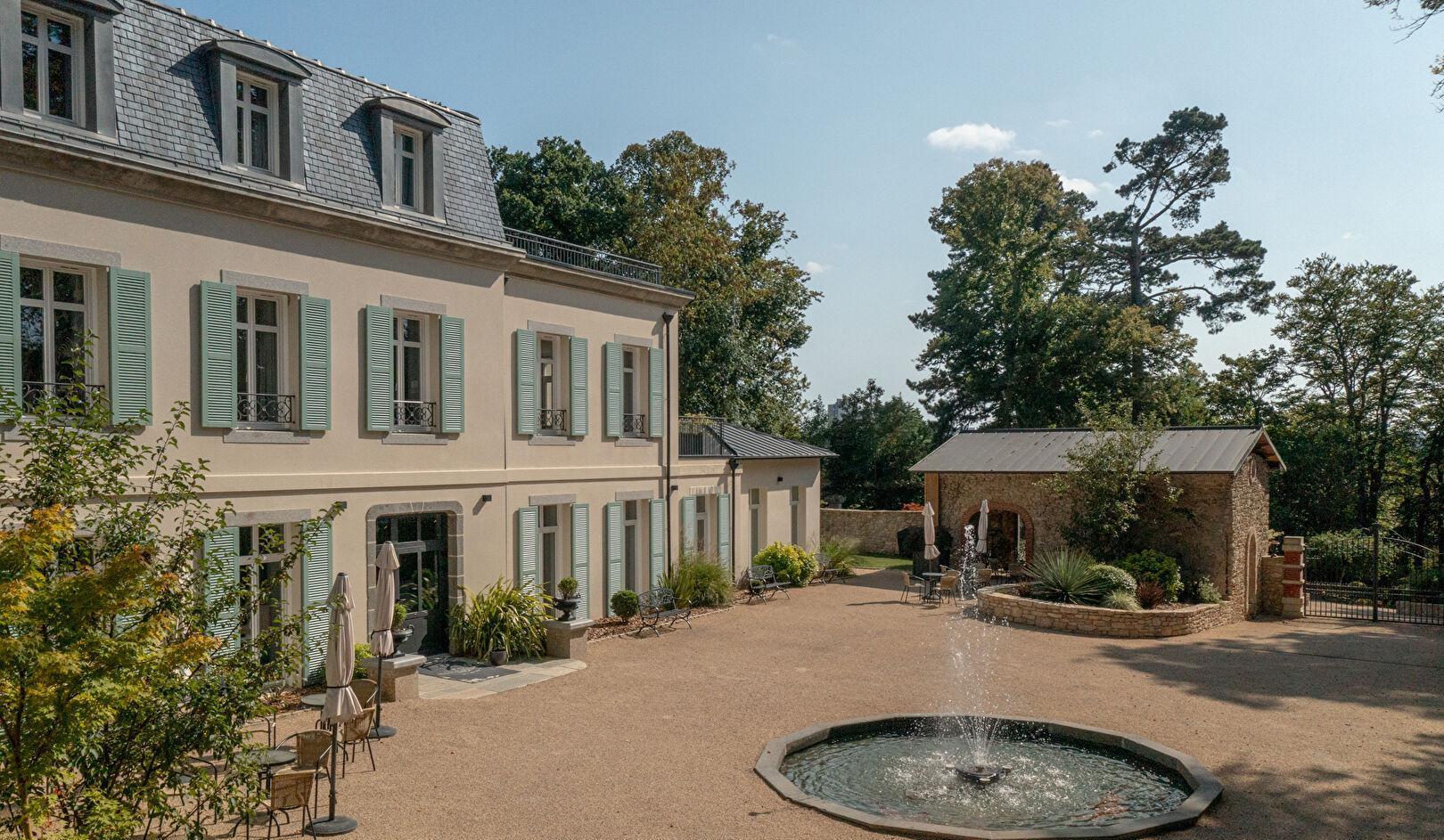 Demeure de caractère en pierre aux volets bleu-gris, avec cour et bassin à fontaine