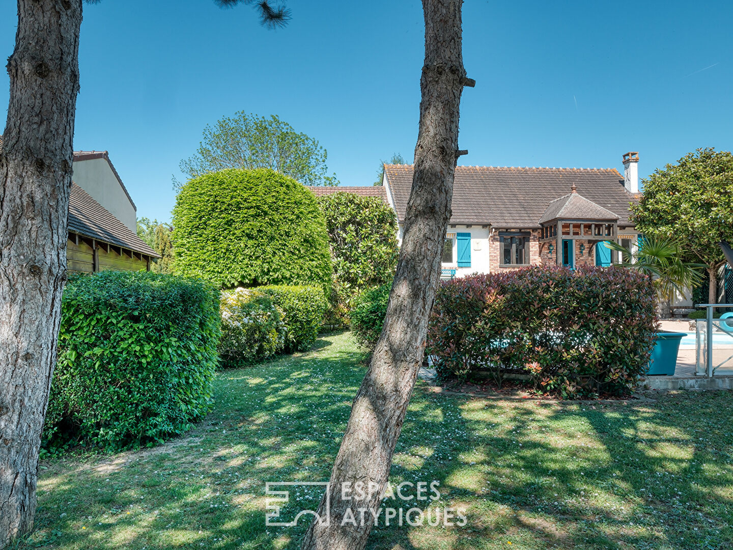 Maison familiale avec jardin paysager, piscine et dépendance.