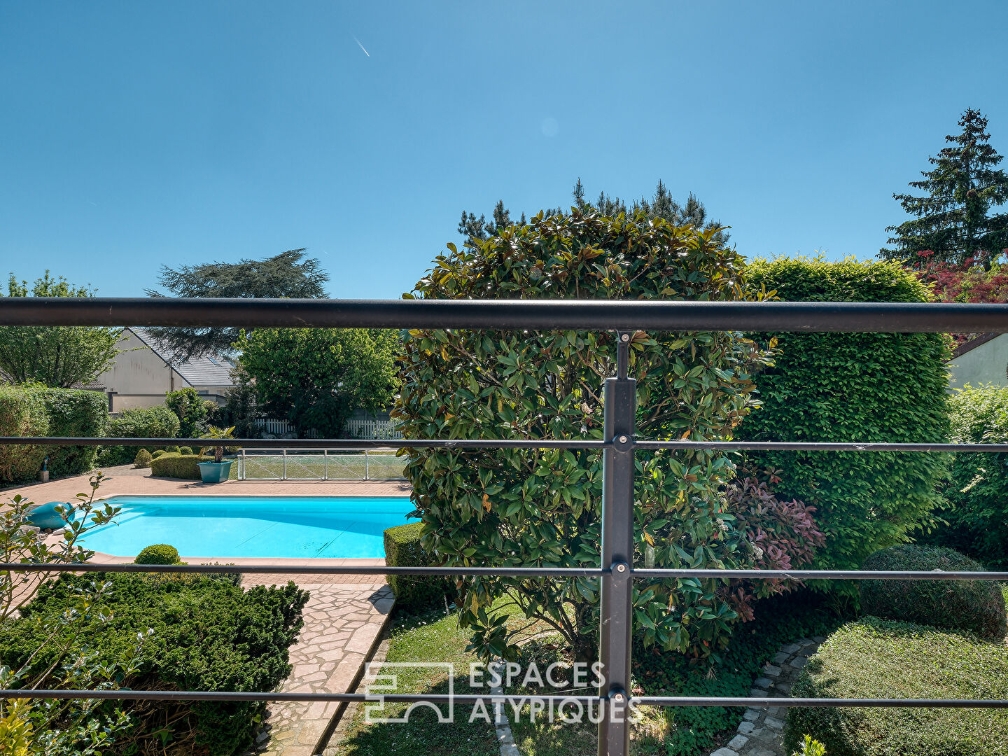 Maison familiale avec jardin paysager, piscine et dépendance.