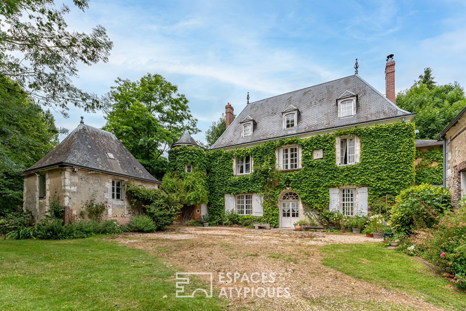 17th century manor and its turret in the heart of a wooded park with outbuildings