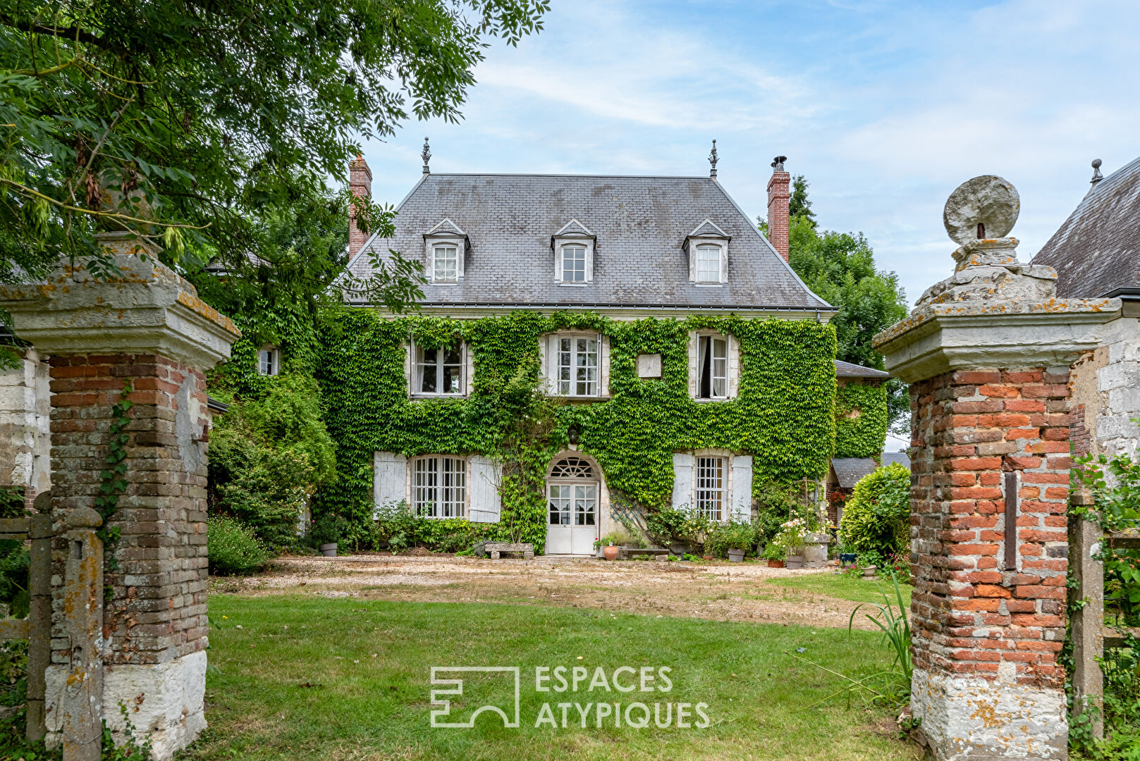 17th century manor and its turret in the heart of a wooded park with outbuildings