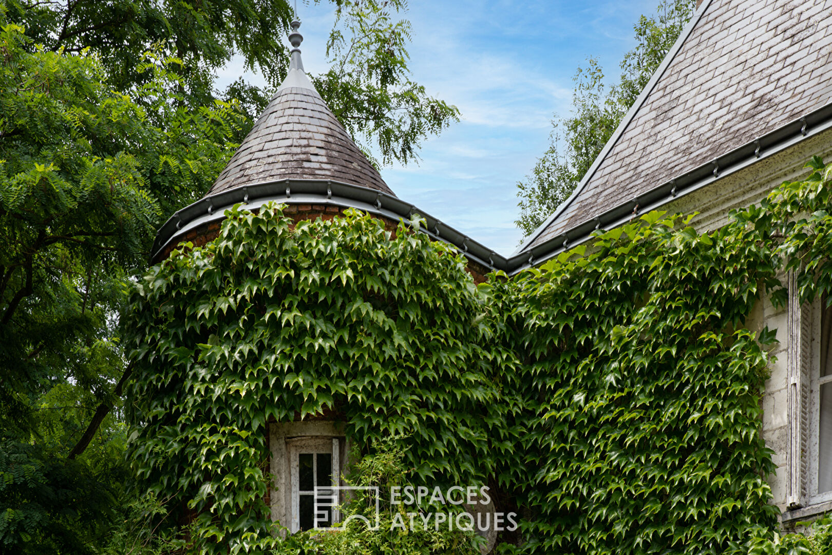 17th century manor and its turret in the heart of a wooded park with outbuildings