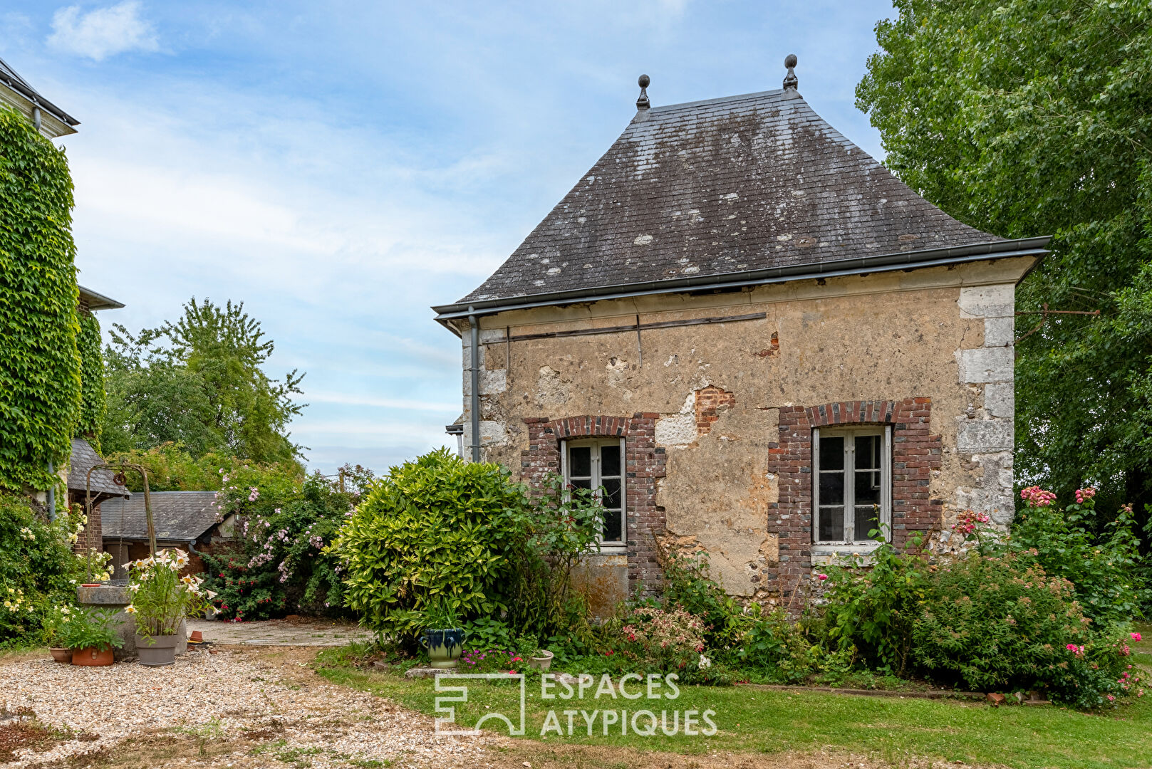 17th century manor and its turret in the heart of a wooded park with outbuildings