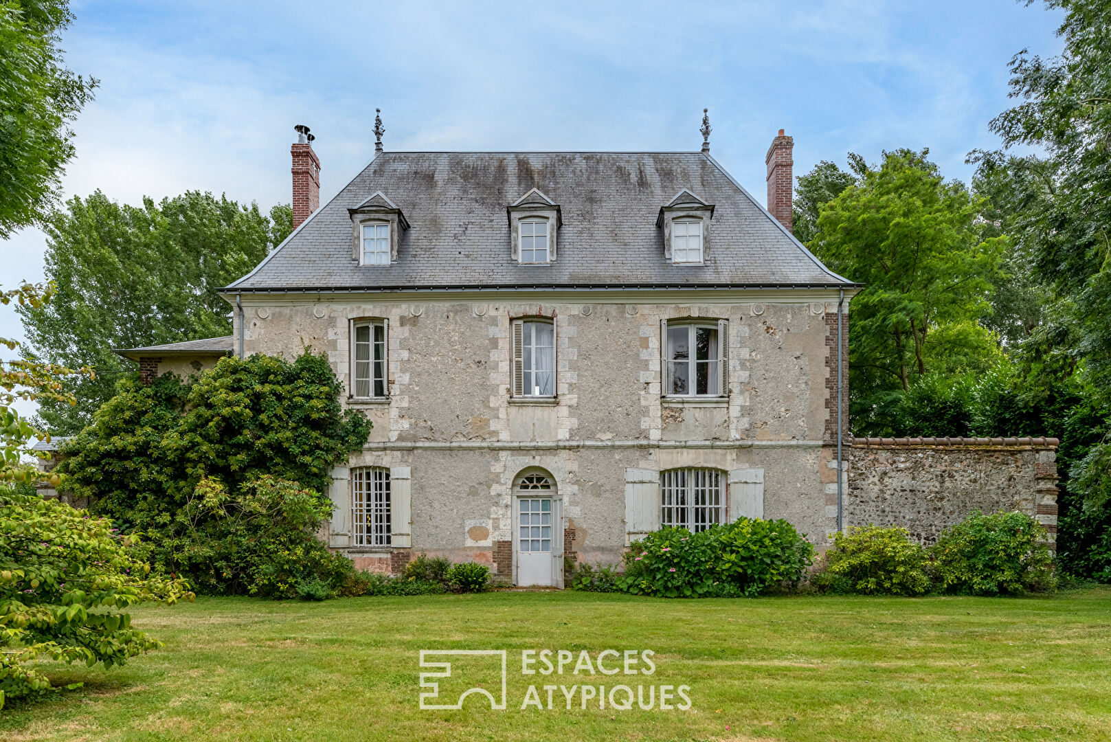 17th century manor and its turret in the heart of a wooded park with outbuildings