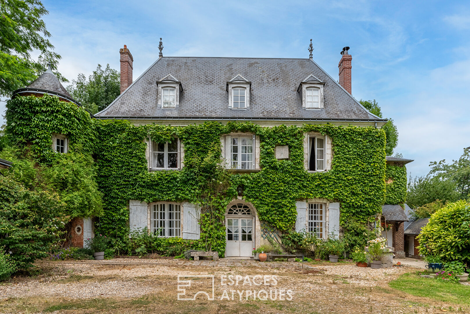 17th century manor and its turret in the heart of a wooded park with outbuildings