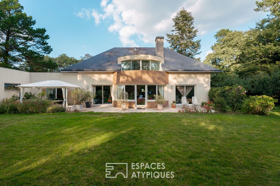 Maison d'Architecte avec jardin paysager dans un environnement boisé.